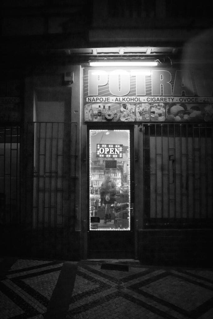 Monochrome photo of an open store at night, highlighting urban architecture.